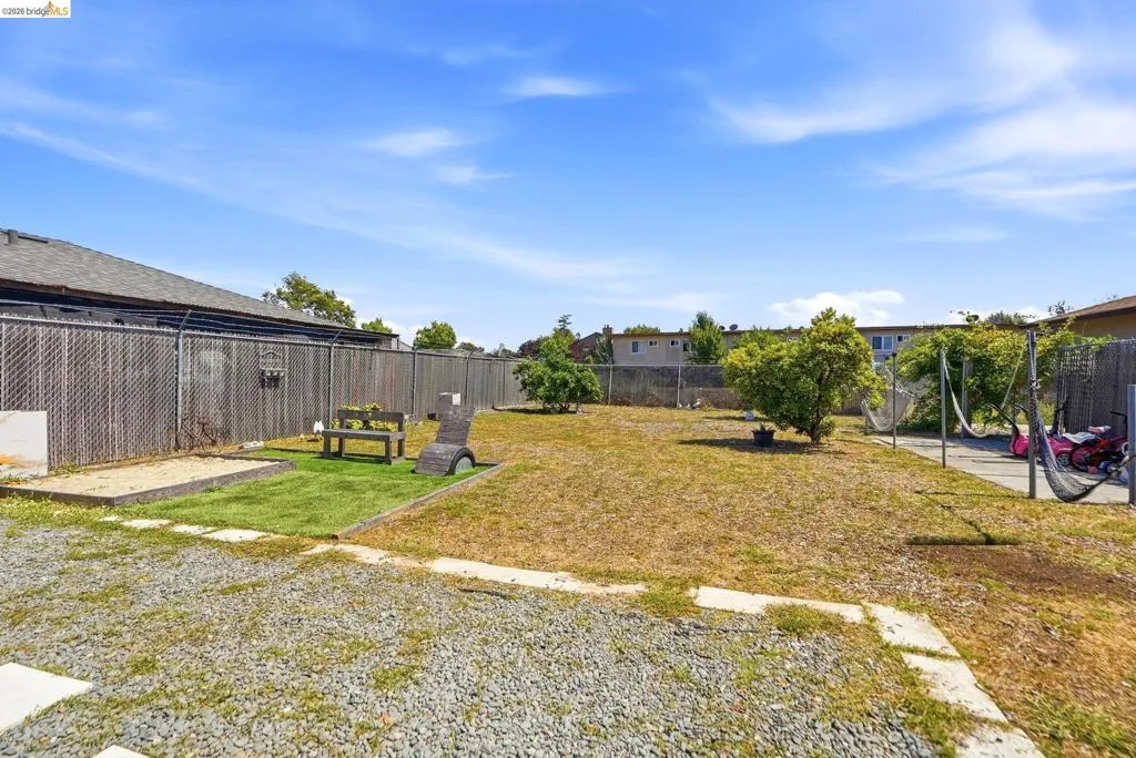 Expansive outdoor area featuring varied ground cover, chain link fencing, and mature plantings