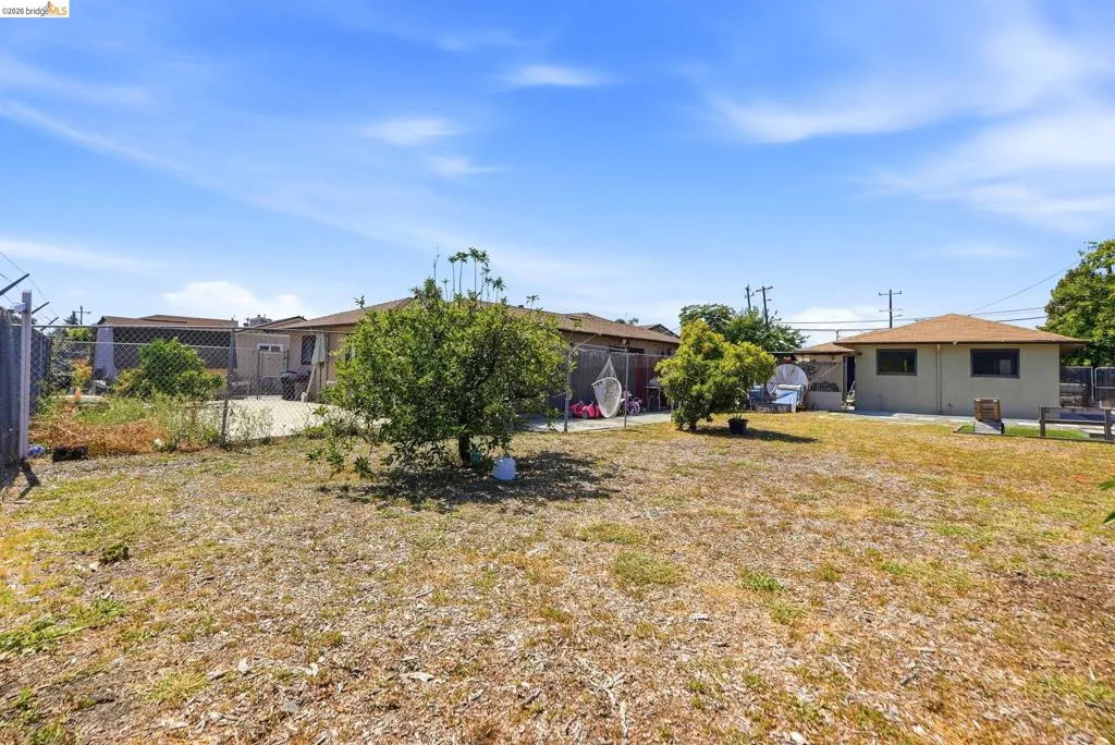Expansive property featuring a chain-link fence, mature trees, and a detached structure