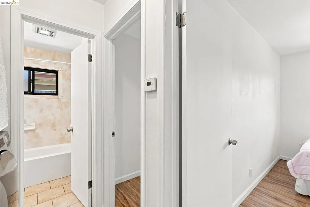Bathroom featuring a white bathtub, tiled shower surround, frosted window, and tiled flooring