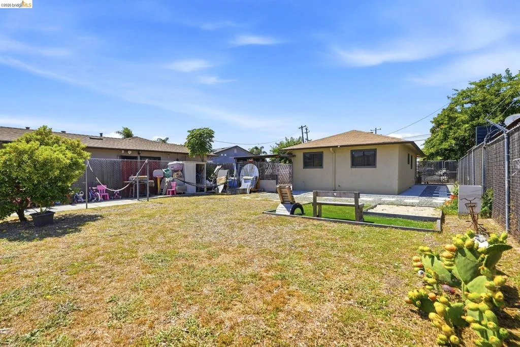 Expansive backyard featuring a large grass area, mature perimeter fencing, and a dedicated gravel section
