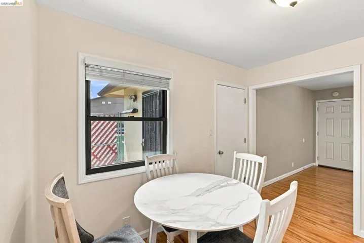 Bright dining area featuring a marble-top round table, white vertical-slat chairs, and warm wood-finish flooring