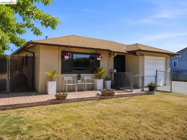 Exterior featuring stucco siding, attached garage, composition shingle roof, and a paved brick patio