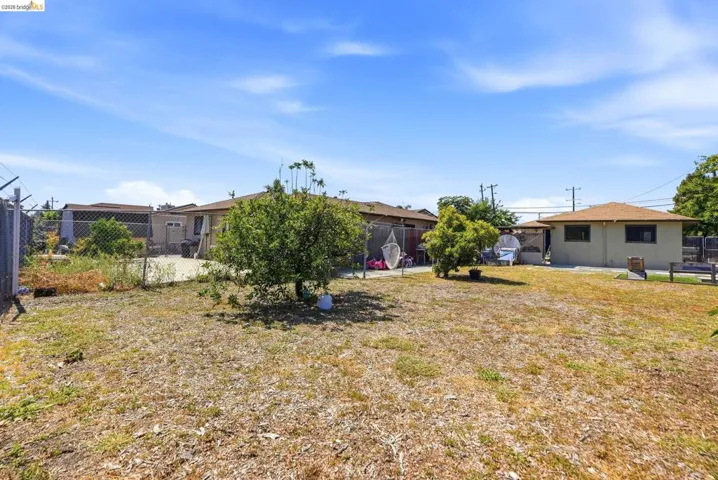 Expansive property featuring a chain-link fence, mature trees, and a detached structure