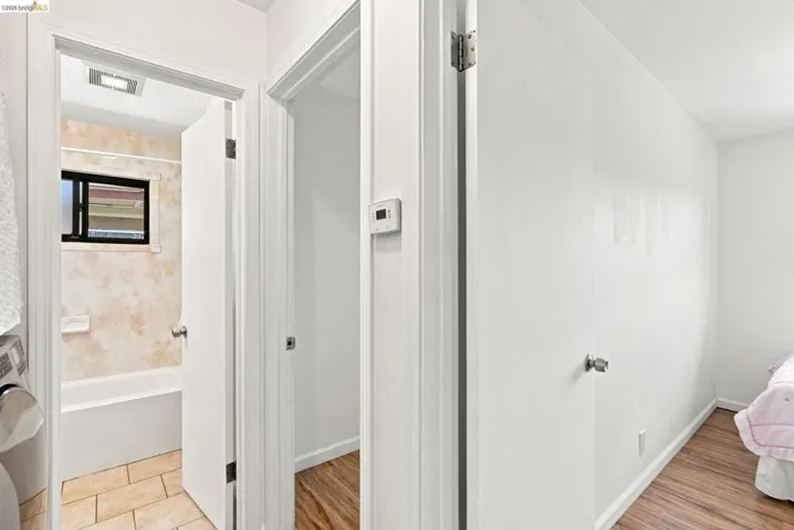 Bathroom featuring a white bathtub, tiled shower surround, frosted window, and tiled flooring
