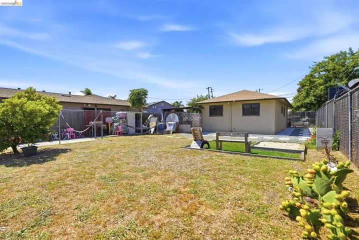 Expansive backyard featuring a large grass area, mature perimeter fencing, and a dedicated gravel section