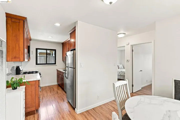 Kitchen featuring wood-finish cabinetry, stainless steel appliances, light-toned countertops, and a tiled backsplash