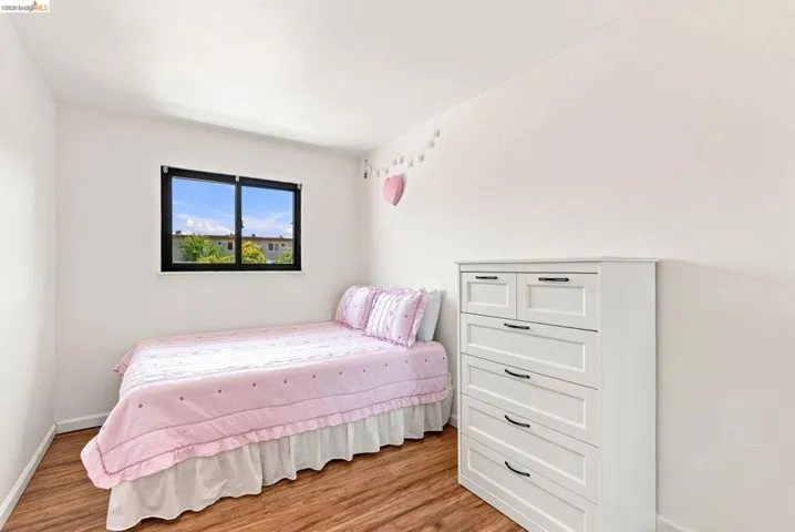 Wood-finish flooring with white walls and a black-framed window