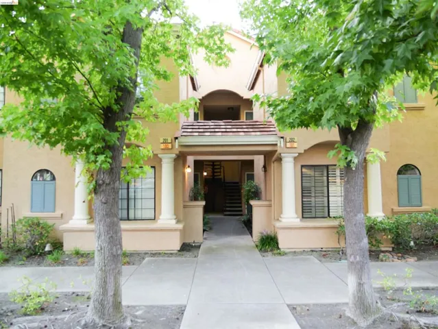 Stucco exterior building with terracotta roof tiles, arched entryway, and prominent columns