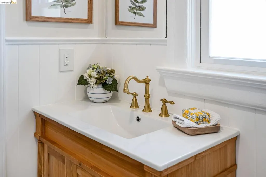 Wood-finish vanity with an integrated sink and brass-finish faucet