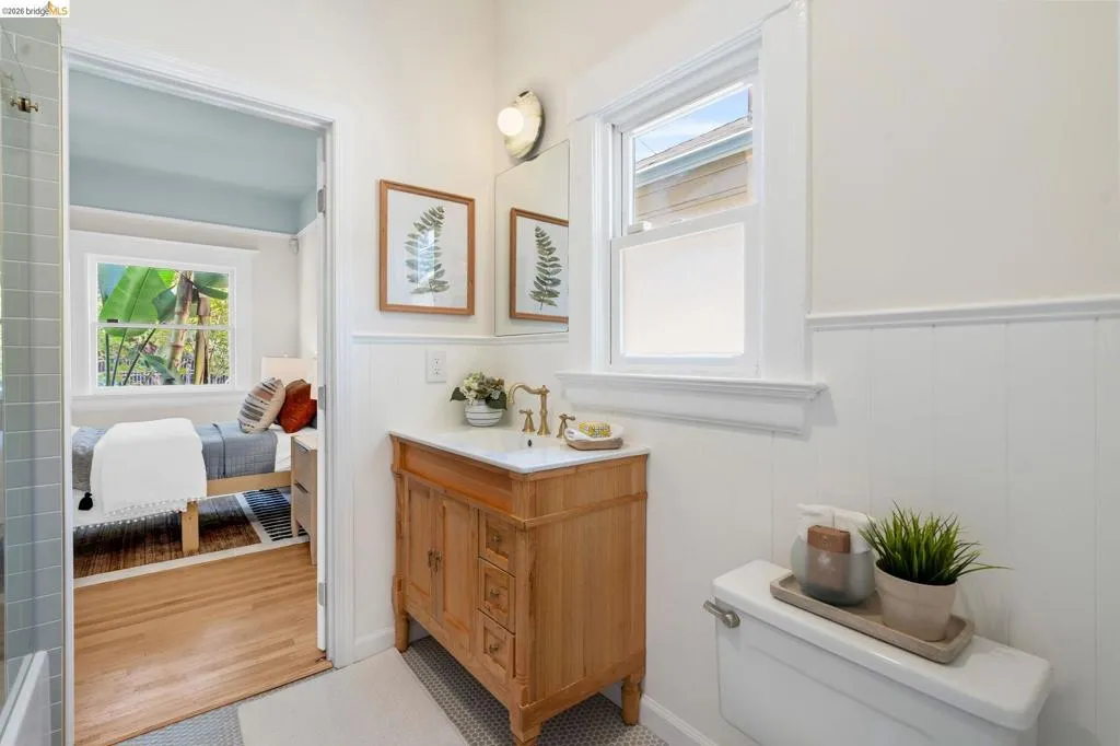 Bathroom featuring a wood vanity with a white countertop and brass-finish faucet, white paneled wainscoting, and a single window