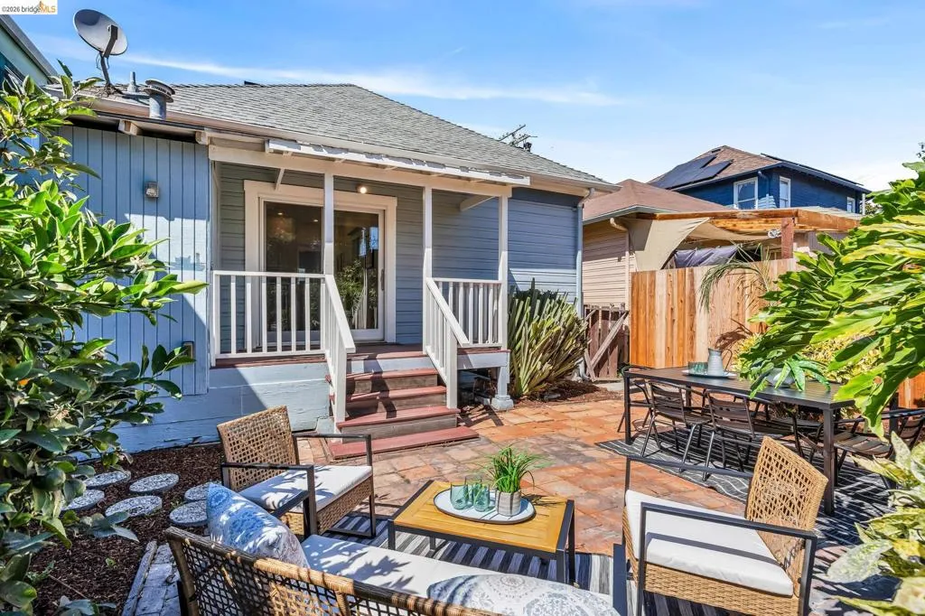 Rear exterior featuring a covered porch with white railings, a sliding glass door, and a paver patio