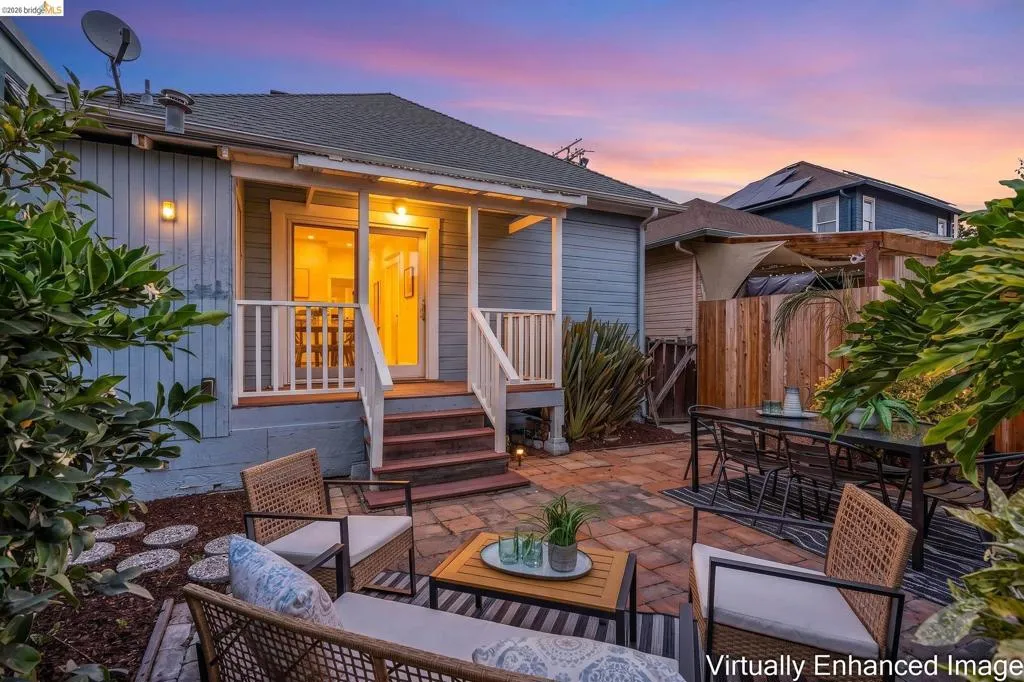 Patio with brick-finish pavers, covered porch entry, wood privacy fence, and mature landscaping