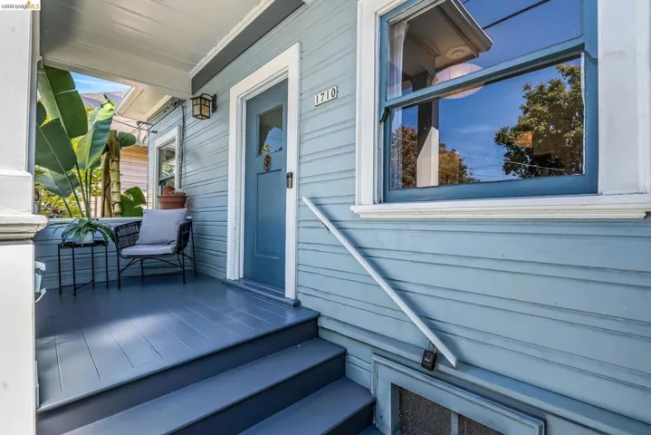 Covered front porch featuring a wood-plank floor, painted siding, and a prominent front door with a window