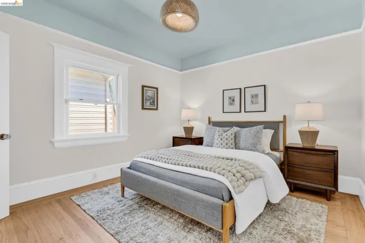 Hardwood flooring with white trim, a single window with white framing, and a light blue painted ceiling