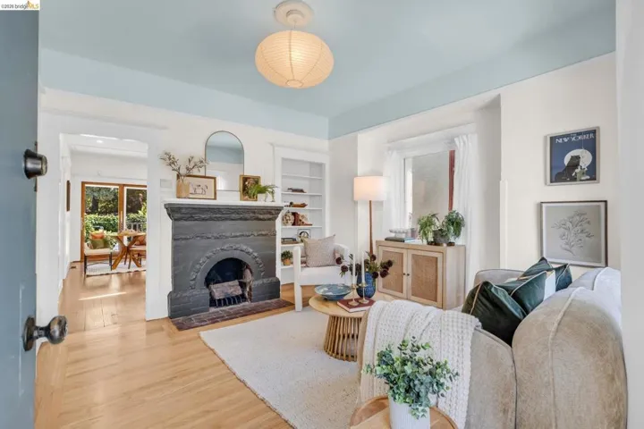 Hardwood flooring throughout, a decorative fireplace with an ornate mantel, built-in shelving, a large window, and an overhead paper lantern light fixture