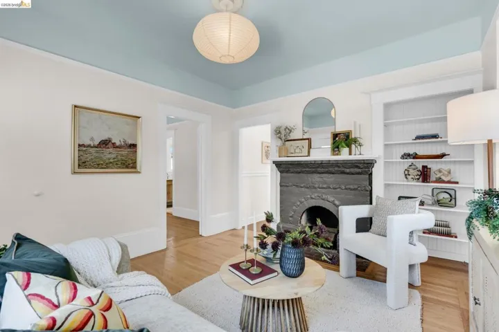 Hardwood flooring, decorative fireplace, built-in shelving, architectural archway, and overhead lighting fixture