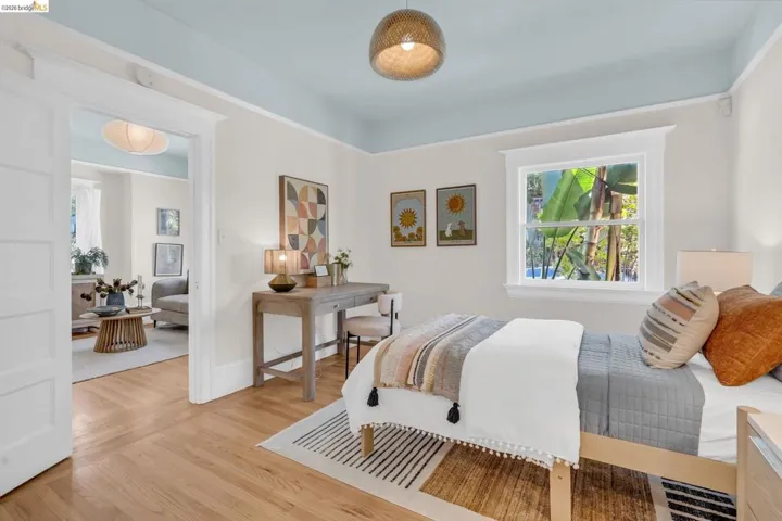 Hardwood flooring, light blue ceiling, white window trim, and a woven pendant light fixture