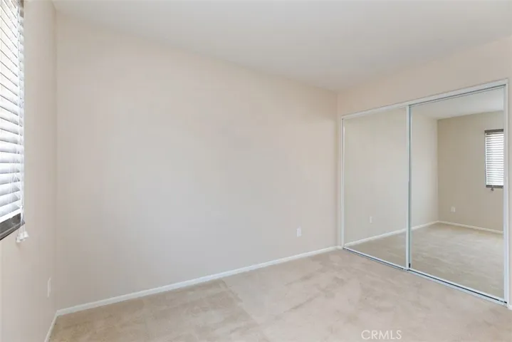 Secondary bedroom, with mirrored closet and wood-blind shades. *flooring to be updated with LVP prior to move-in.