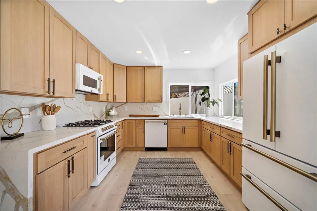 Designed to impress, the kitchen features quartz countertops & backsplash w/waterfall edges, custom soft-close cabinetry & drawers, dramatic black & antique-brass hardware, and a complete suite of professional Forno appliances accented with antique-brass handles.