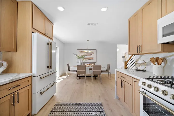 the kitchen features quartz countertops & backsplash w/waterfall edges, custom soft-close cabinetry & drawers, dramatic black & antique-brass hardware, and a complete suite of professional Forno appliances