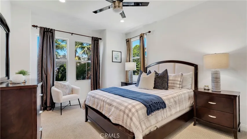 Main-level bedroom with abundant natural light, ceiling fan, and generous space for furnishings