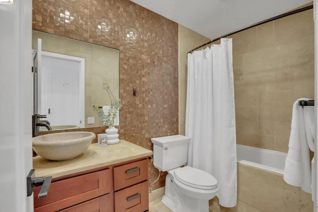 Vanity with stone vessel sink, dark wood cabinetry, and a stone countertop