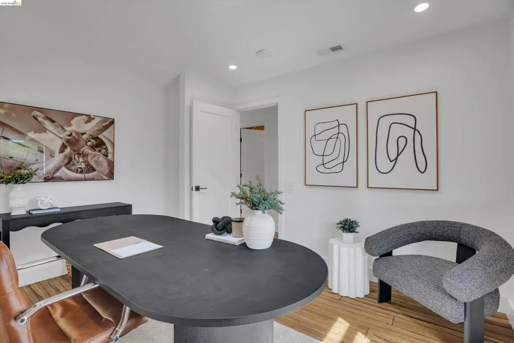 Recessed lighting, wood-finish flooring, white walls, and a white interior door with black hardware