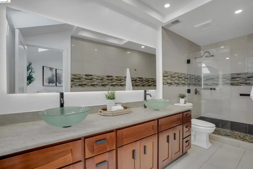 Dual glass vessel sinks set on a wood-finish vanity with a light-toned countertop
