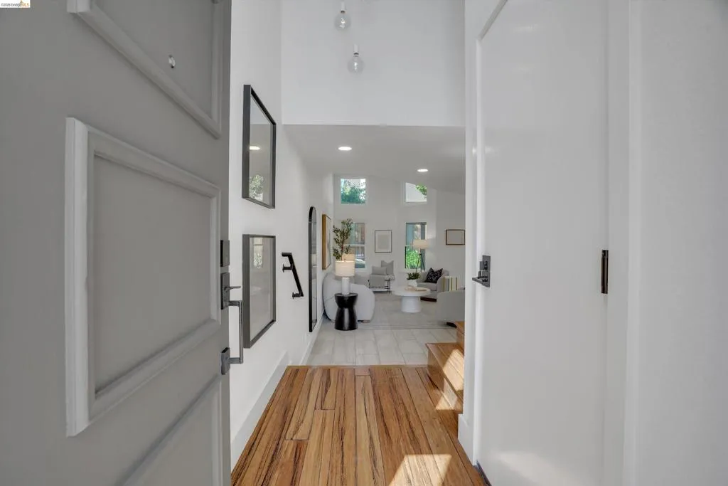 Wood-finish flooring leading to an open living area with vaulted ceilings and recessed lighting