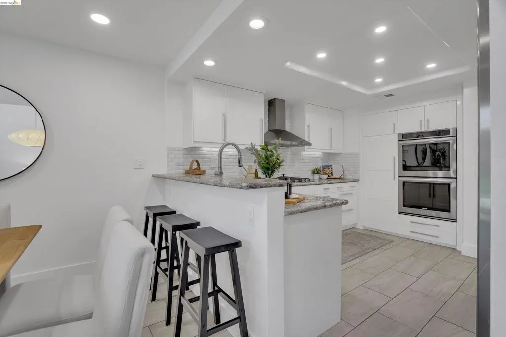Kitchen featuring white cabinetry, subway tile backsplash, stainless steel appliances, granite countertops, and recessed lighting