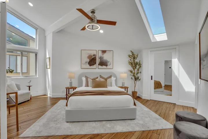 Vaulted ceiling with exposed beam, wood-finish flooring, large skylight, recessed lighting, and a modern ceiling fan