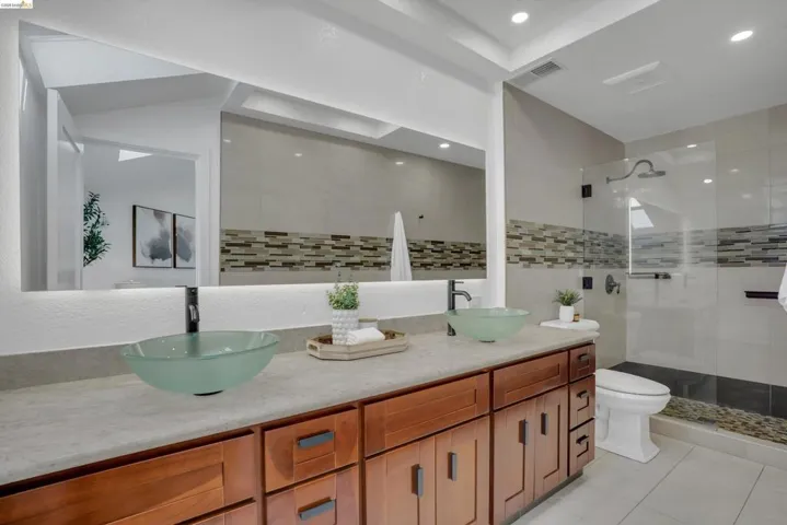 Dual glass vessel sinks set on a wood-finish vanity with a light-toned countertop