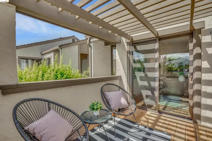 Outdoor patio featuring a slatted pergola, exterior wall, and wood-finish flooring