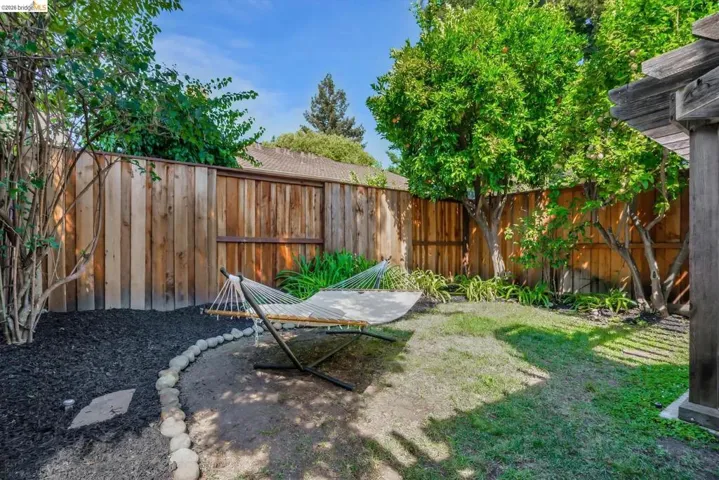 Private backyard featuring mature trees, a manicured lawn, and natural wood fencing