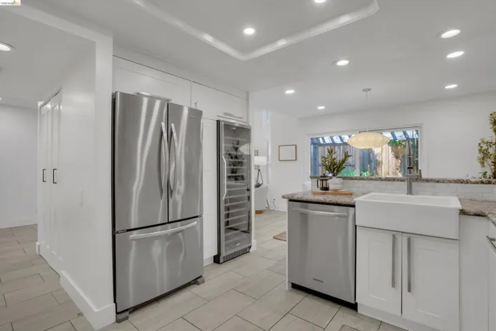 Kitchen featuring recessed lighting, a white farmhouse sink, stainless steel appliances, white cabinetry, and light-toned tile flooring