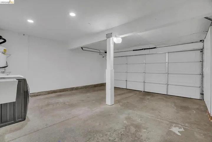 Attached garage with a white sectional door, concrete flooring, and recessed ceiling lighting