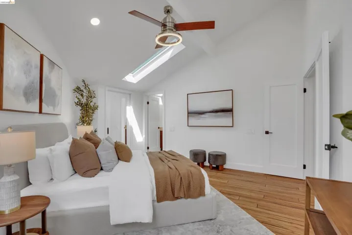 Vaulted ceilings, skylight, wood-finish flooring, ceiling fan with integrated lighting, and white paneled doors