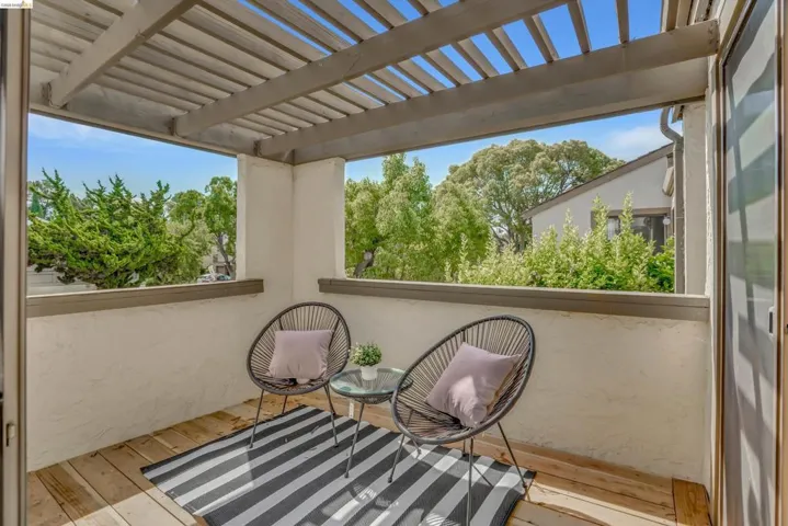 Outdoor patio featuring wood-finish decking, a slatted pergola, stucco walls, and an exterior glass sliding door