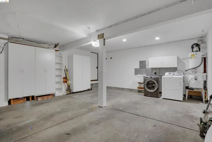 Spacious utility area featuring multiple storage cabinets, built-in shelving, a utility sink, and a water heater