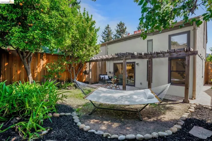 Private backyard featuring a pergola, wood fencing, and a stucco exterior