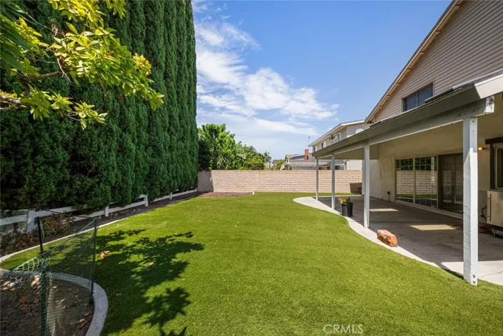 Established trees line the block wall fence that encloses the yard.