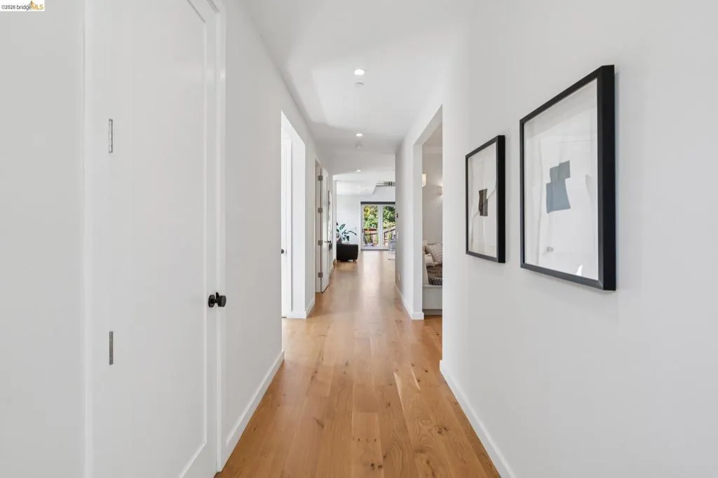 Recessed lighting illuminates the hallway, featuring wood-finish flooring and white walls Recessed lighting illuminates the hallway, featuring wood-finish flooring and white walls