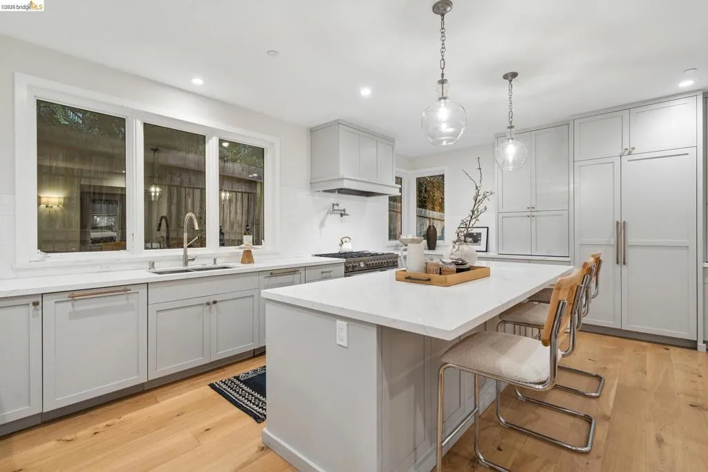 Light-toned wood-finish flooring, white countertops, gray cabinetry, recessed lighting, and a kitchen island with pendant lighting Light-toned wood-finish flooring, white countertops, gray cabinetry, recessed lighting, and a kitchen island with pendant lighting