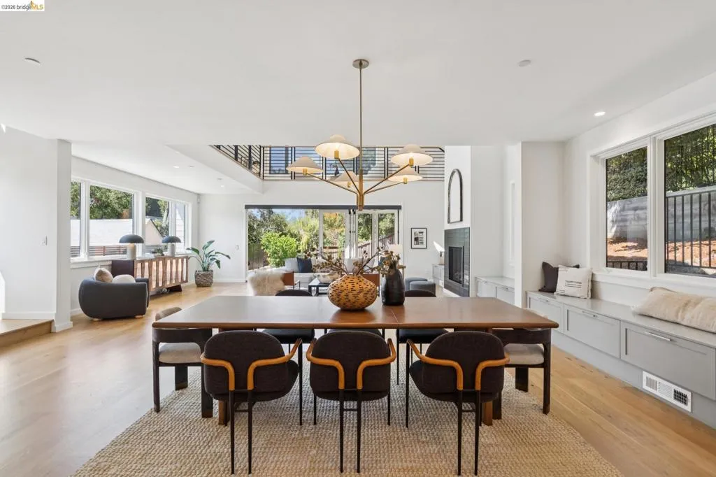Expansive open-concept living area featuring wood-finish flooring, a contemporary chandelier, and a built-in window bench with storage Expansive open-concept living area featuring wood-finish flooring, a contemporary chandelier, and a built-in window bench with storage