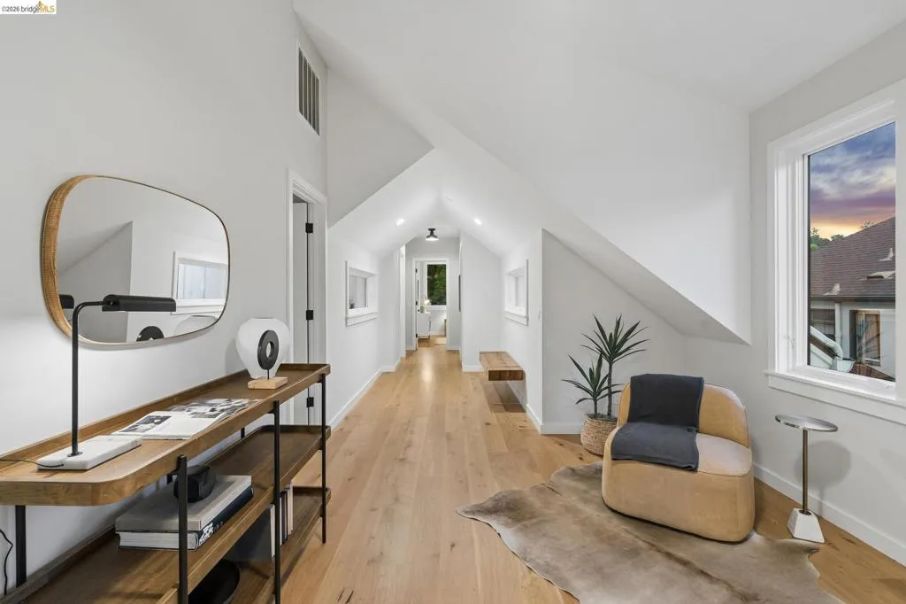 Vaulted ceilings with recessed lighting, light wood-finish flooring, white window frames, and a built-in wall niche Vaulted ceilings with recessed lighting, light wood-finish flooring, white window frames, and a built-in wall niche