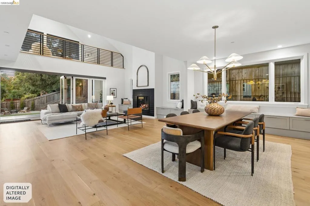 Vaulted ceilings, wood-finish flooring, a contemporary chandelier, a built-in fireplace with a dark surround, and a folding glass door system leading to the exterior Vaulted ceilings, wood-finish flooring, a contemporary chandelier, a built-in fireplace with a dark surround, and a folding glass door system leading to the exterior
