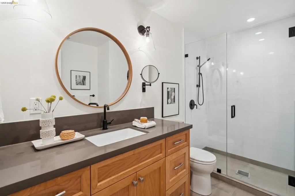 Wood-finish vanity with a rectangular undermount sink, dark countertop, and matte black faucet Wood-finish vanity with a rectangular undermount sink, dark countertop, and matte black faucet