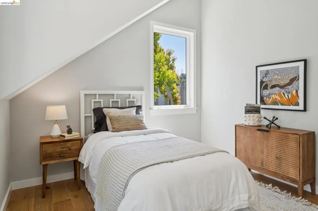 Sloped ceiling design, light wood-finish flooring, white window frame, and neutral wall paint Sloped ceiling design, light wood-finish flooring, white window frame, and neutral wall paint