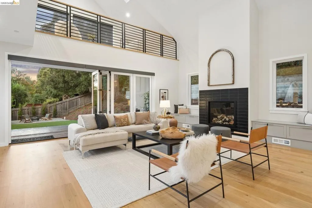 High vaulted ceiling, wood-finish flooring, black tile fireplace, bi-fold glass doors, and an upper-level interior balcony High vaulted ceiling, wood-finish flooring, black tile fireplace, bi-fold glass doors, and an upper-level interior balcony