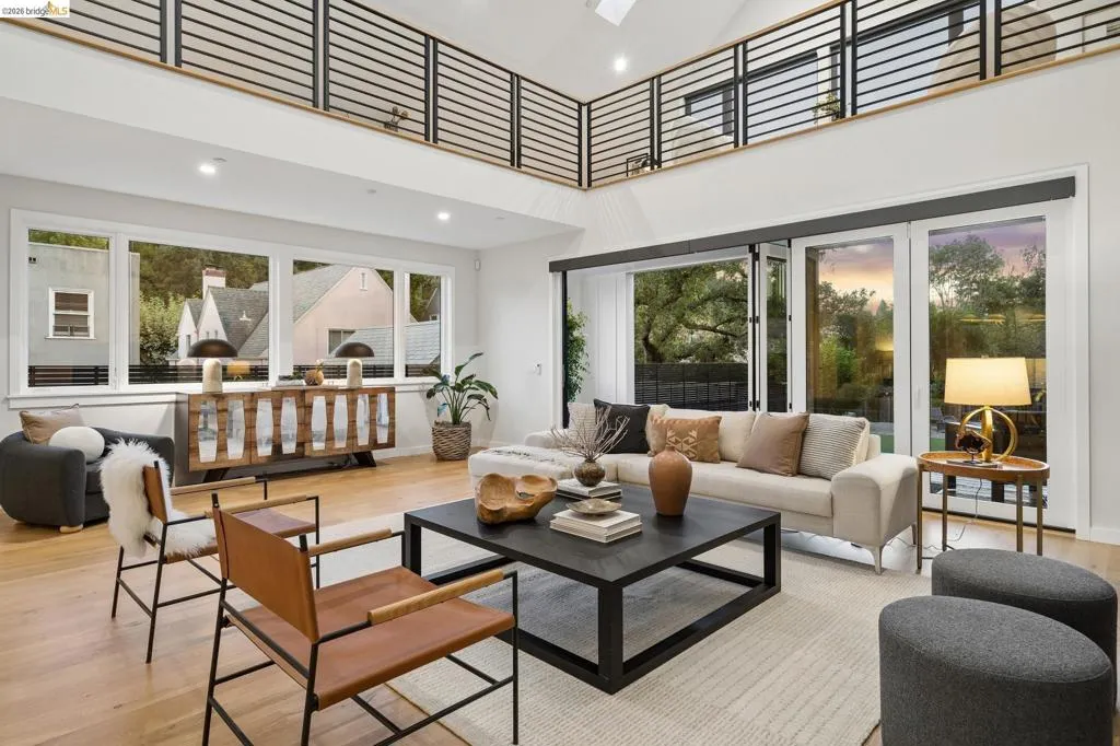 Vaulted ceiling with exposed beams, hardwood flooring, expansive windows, large glass sliding doors, and an interior balcony with black railings Vaulted ceiling with exposed beams, hardwood flooring, expansive windows, large glass sliding doors, and an interior balcony with black railings